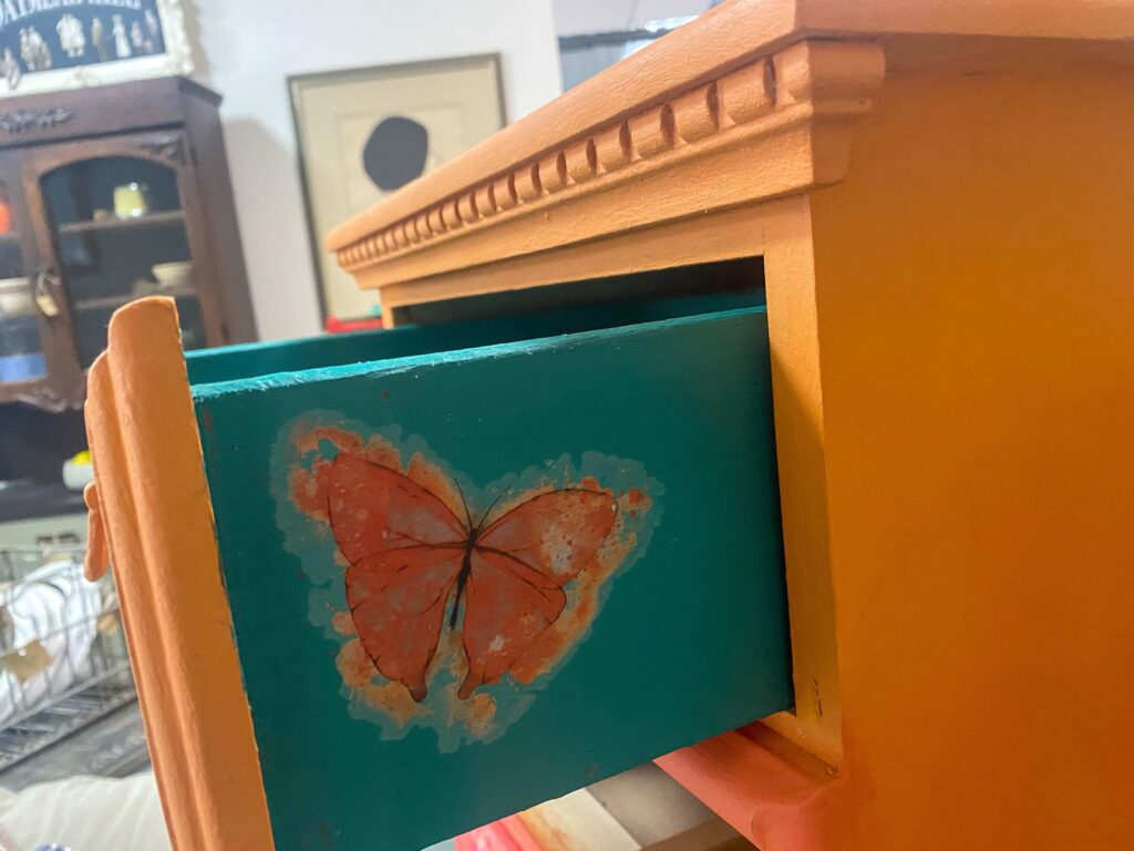Surprise butterfly on side of drawer of an orange dresser.